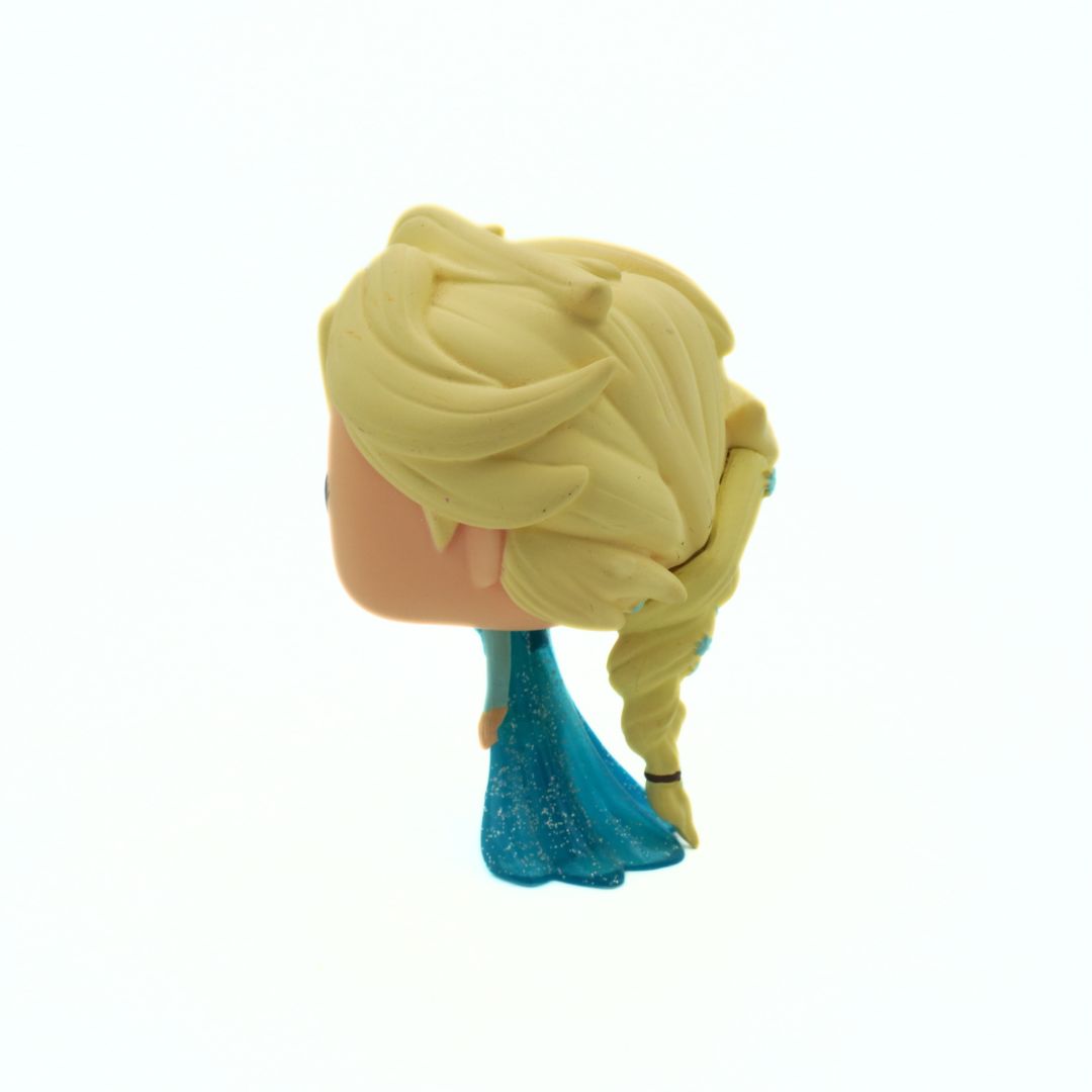 Toy figure of a character with blonde hair and blue dress on a white background