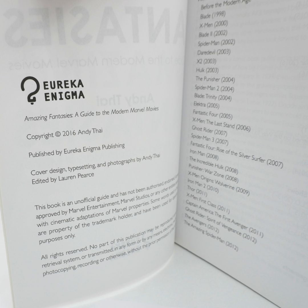 An open book showing printed pages with the title '2 Eureka Enigma' and text about 'Amazing Fantasies: A Guide to the Modern Marvel Movies,' by Andy Thai