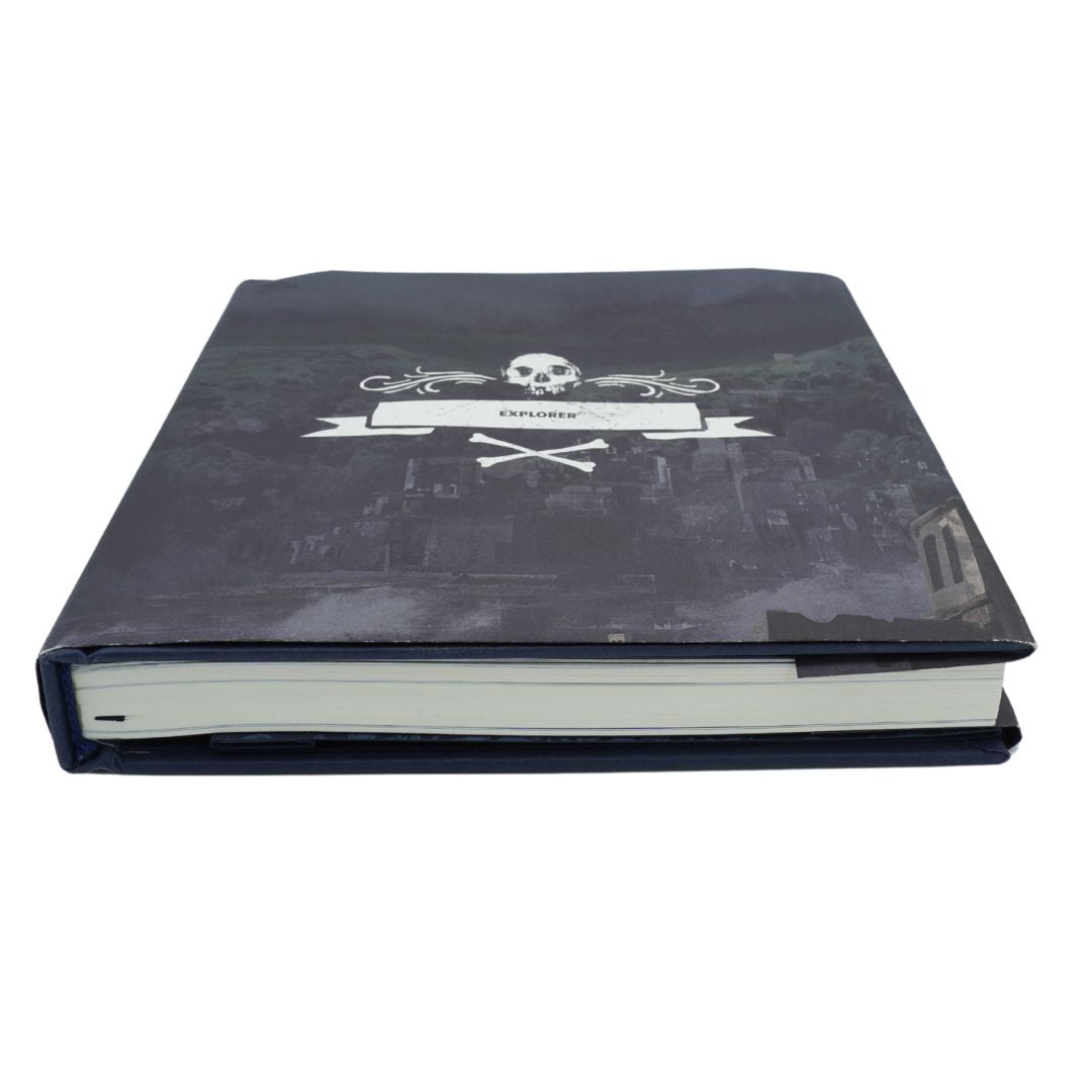 A hardcover journal or book with a dark, gothic-style cover featuring a skull and crossbones emblem with a blank banner that reads 'EXPLORER'. The book is photographed on a clean white background.