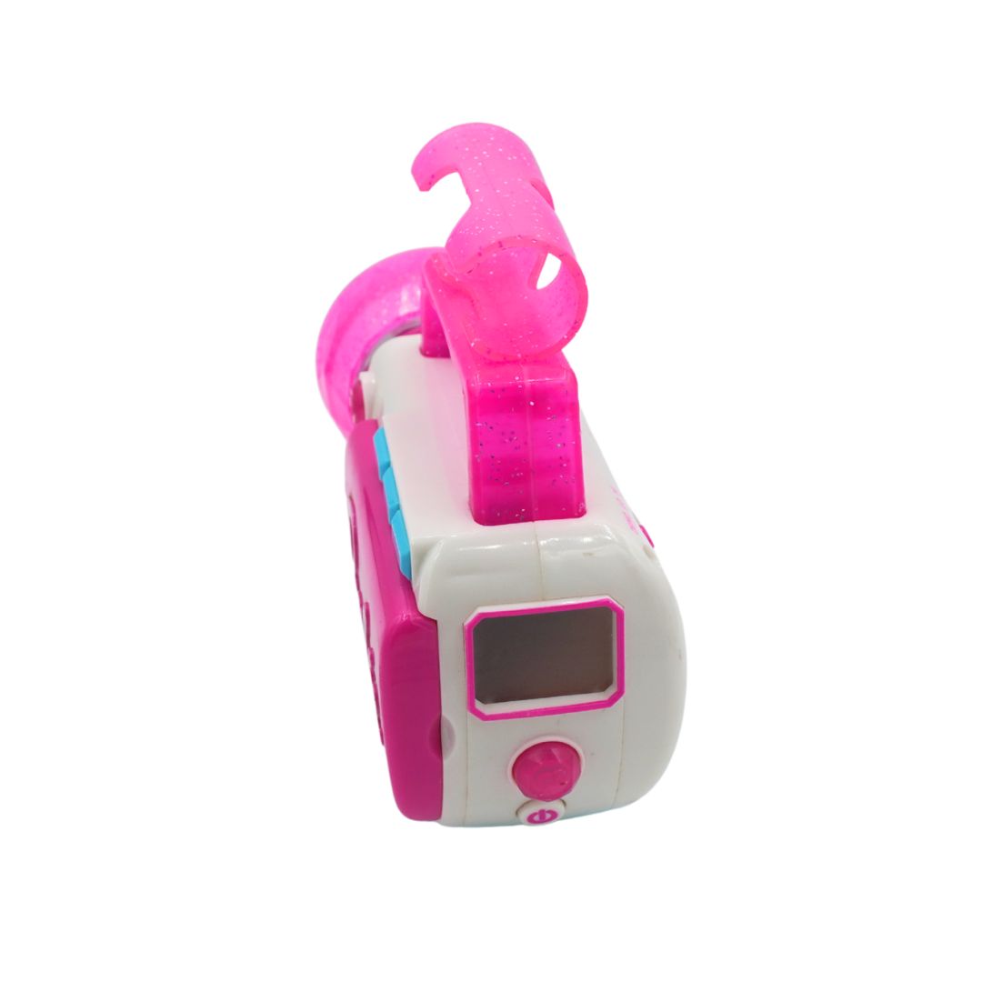 A pink and white plastic toy alarm clock shaped like a retro camper van, featuring a translucent glittery pink handle on top, a small digital display window, and a pink button on the front.