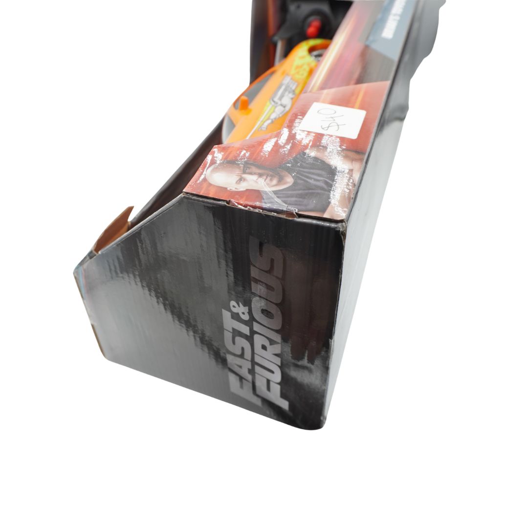 A boxed toy car in its original retail packaging, featuring the 'Fast & Furious' logo on a black box with a clear window showing an orange and yellow toy vehicle inside.