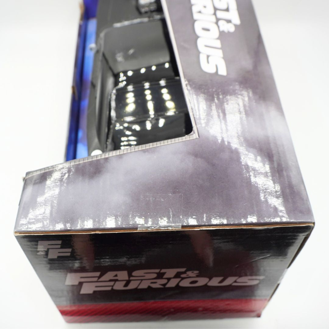 Close-up of a boxed toy car on a white background. The packaging prominently shows the Fast & Furious logo and a window displaying a black die-cast model car.
