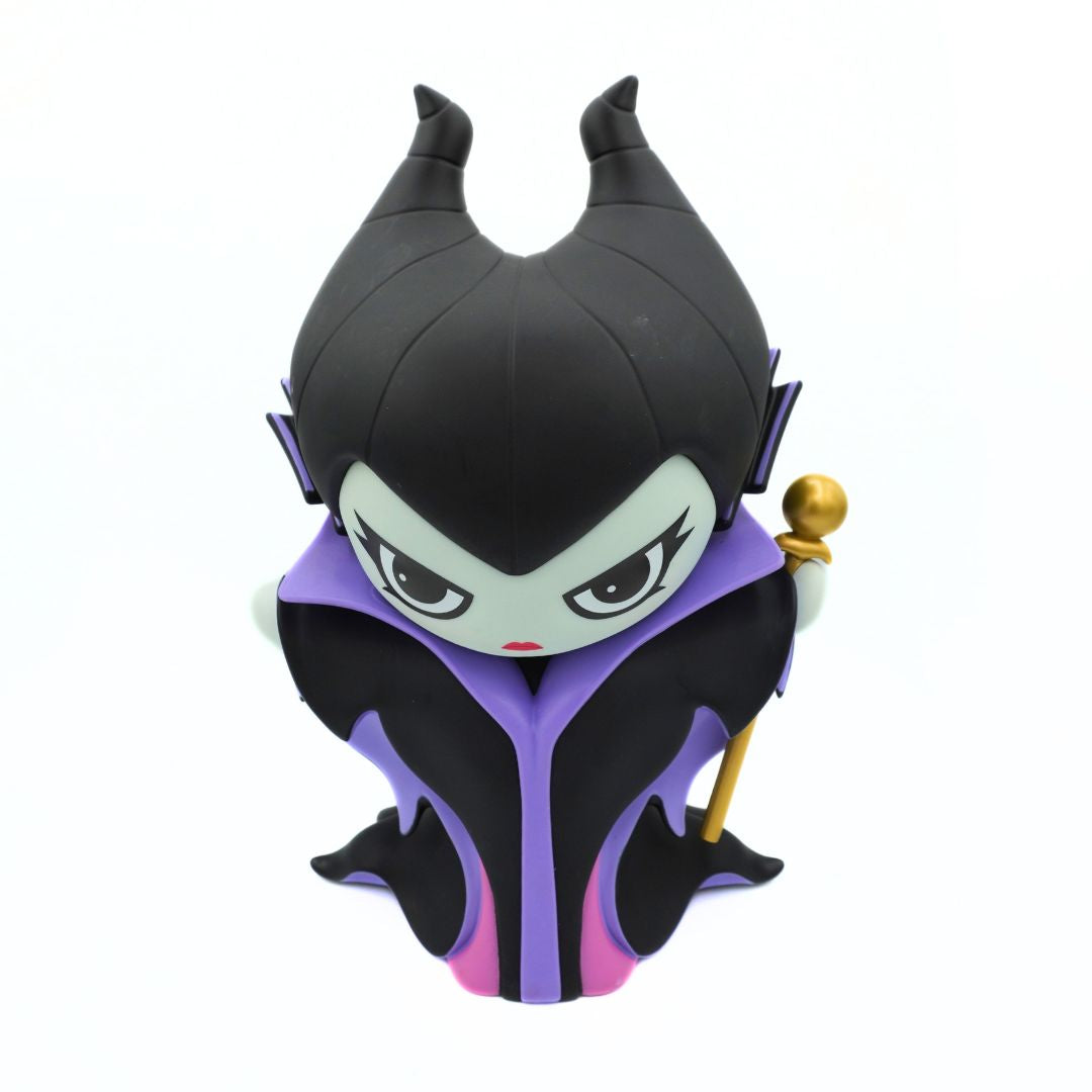 A green figurine wearing a purple and black jacket and black hat, holding a gold rod