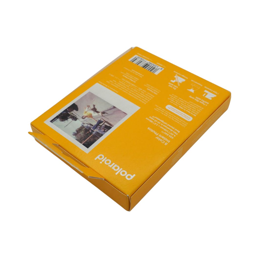Polaroid instant film packaging box shown from the back side, featuring white printed text, a barcode, and a sample instant photo print on a solid orange-yellow background, isolated on a white studio background.