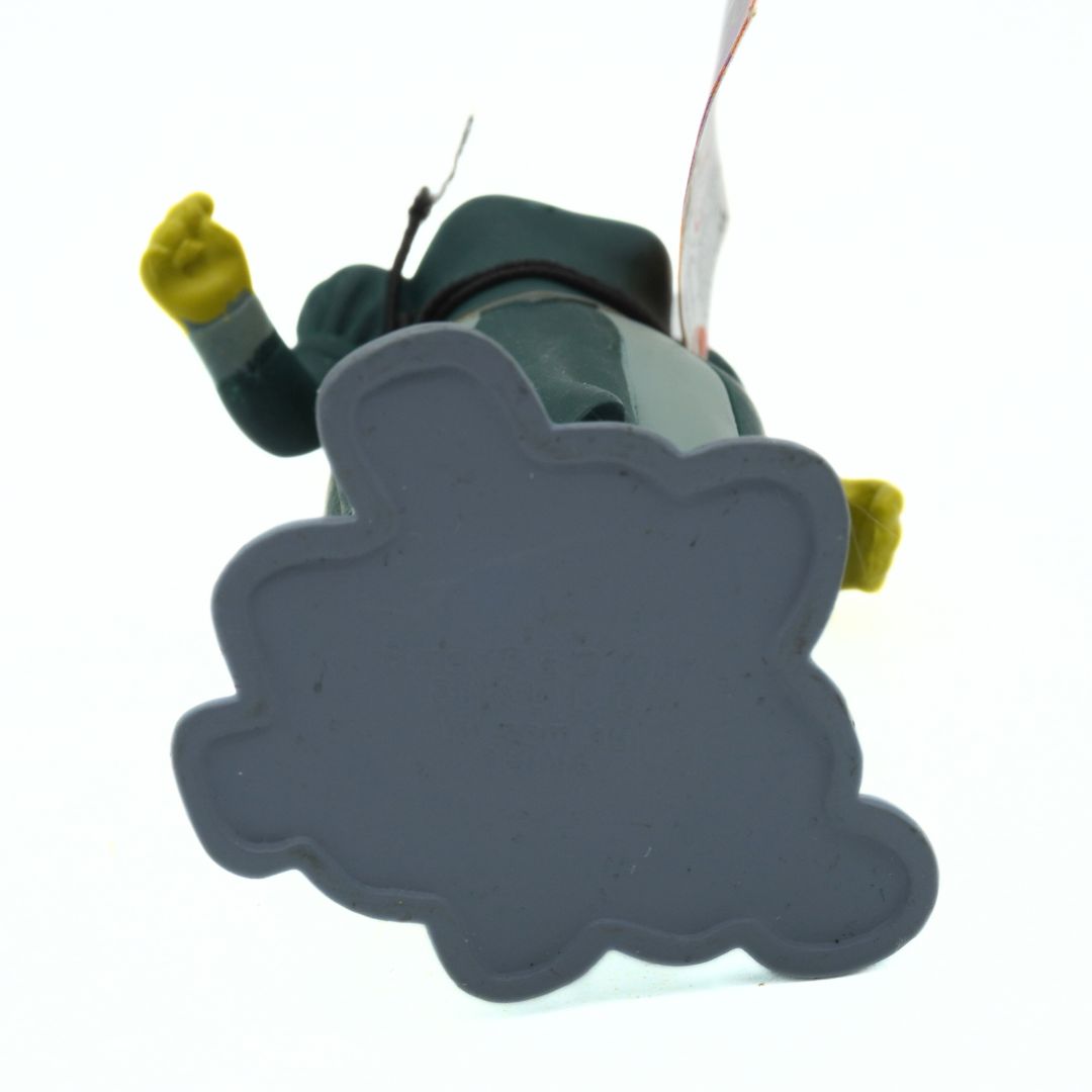 Toy in a green dress standing on grey rocks on a white background