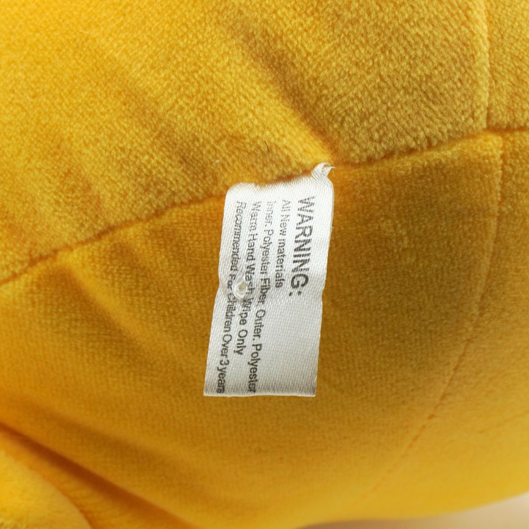 Close-up of a yellow plush toy with a warning label on it.