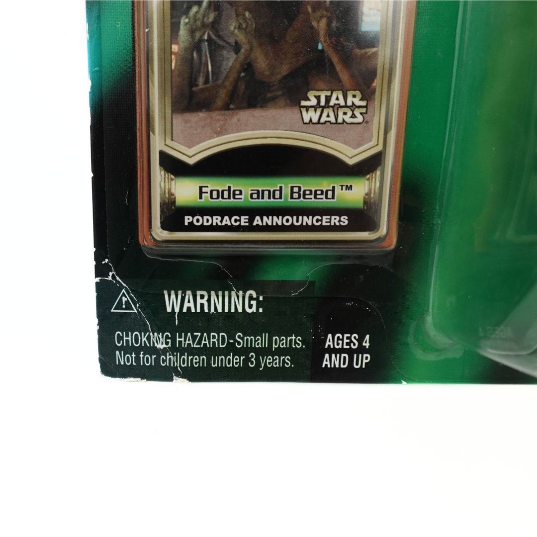 Bottom left corner of the packaging of the Fode and Beed Star Wars Podrace announcers showing some creasing and damage