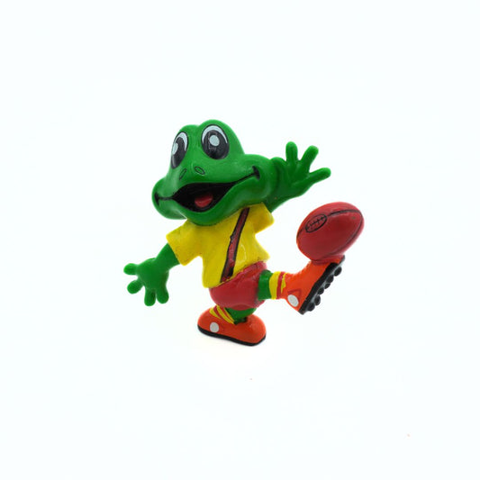 Colorful frog figurine in a yellow shirt with a red ball on a white background
