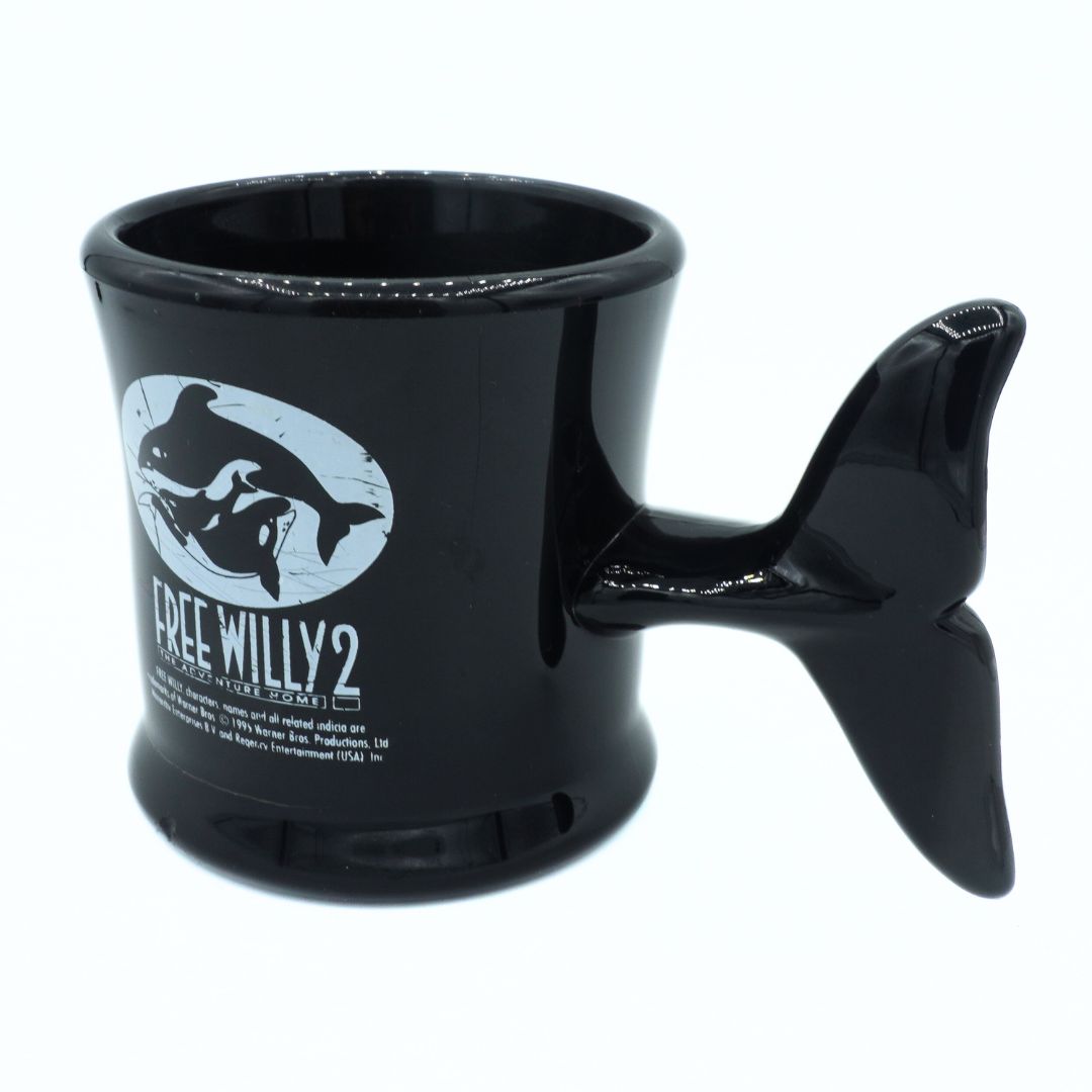 Black mug with whale design and 'Free Willy 2' text on a white background