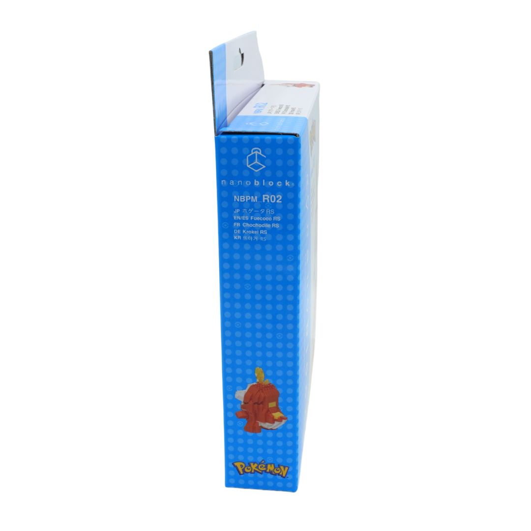 A tall blue cardboard box for a Pokémon buildable toy, featuring the character Fuecoco printed on the side with a small illustration of the red plush toy near the bottom.