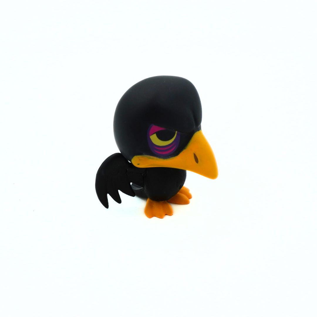 A small black raven figurine with a bright yellow beak, orange feet, and a purple and yellow eye, shown on a plain white background.