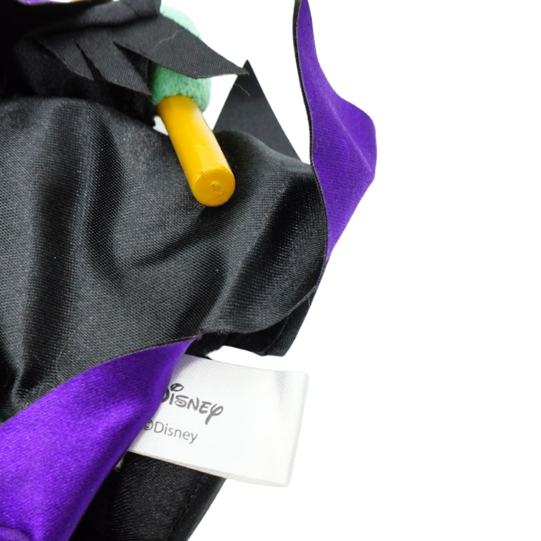 Close-up of a Disney-themed black and purple garment or accessory with a visible white Disney tag and a yellow-and-green cylindrical detail, photographed on a white background.