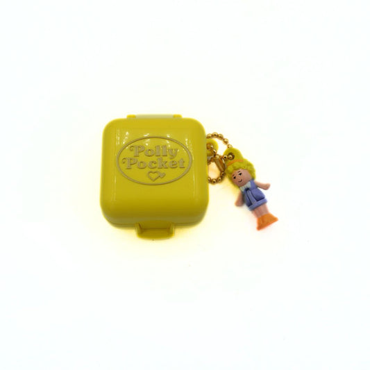 Yellow Polly Pocket case with a character charm on a white background