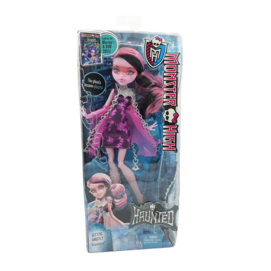 Monster High doll packaging with a purple outfit and pink hair on a white background