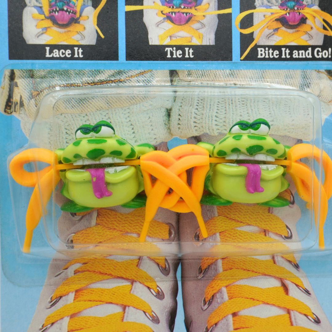 Shoe lace holder with green frog design in packaging
