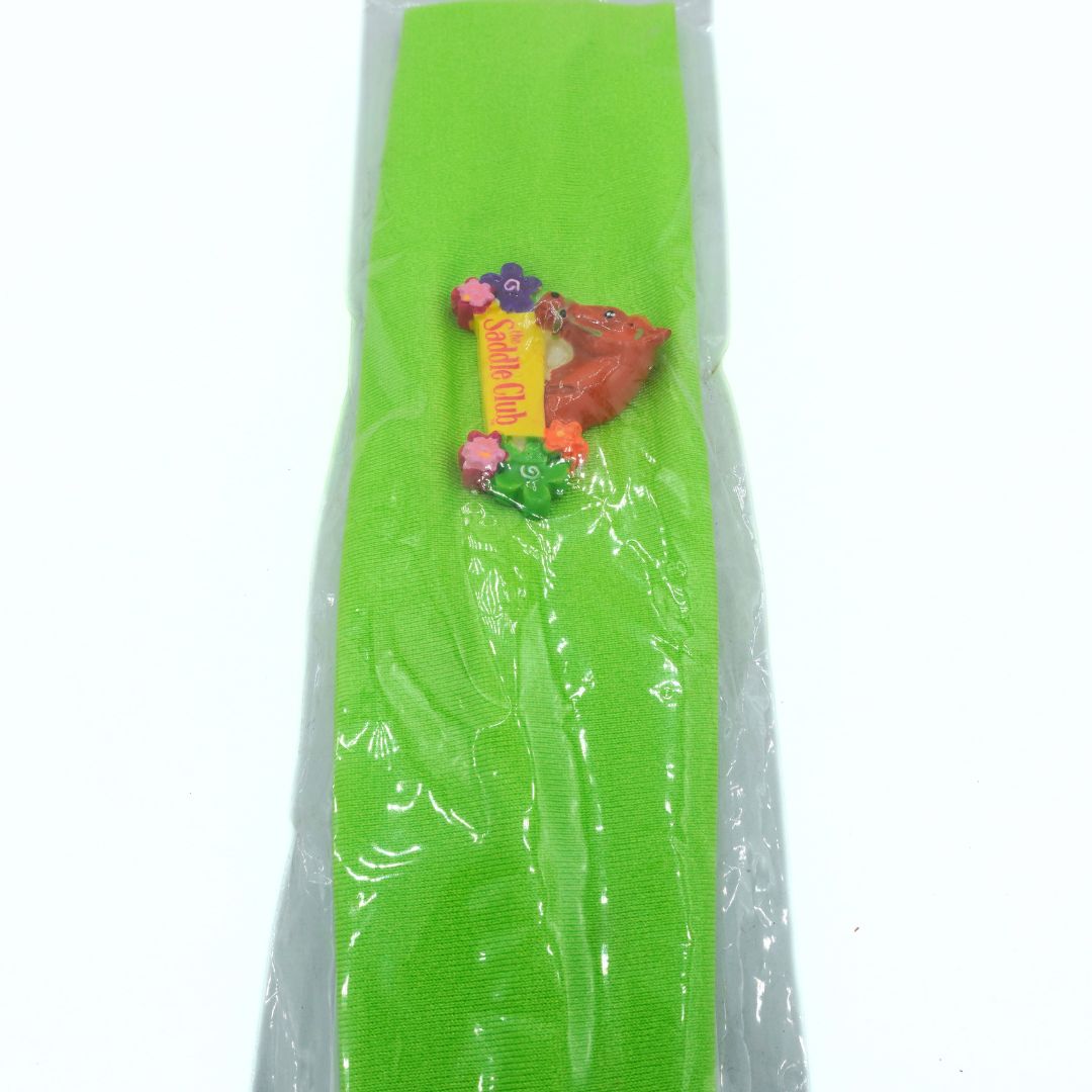 Green Saddle Club headband with a colorful label on a white background