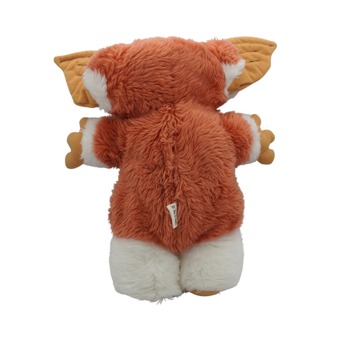 Plush toy resembling a fox with orange fur and white accents on a white background