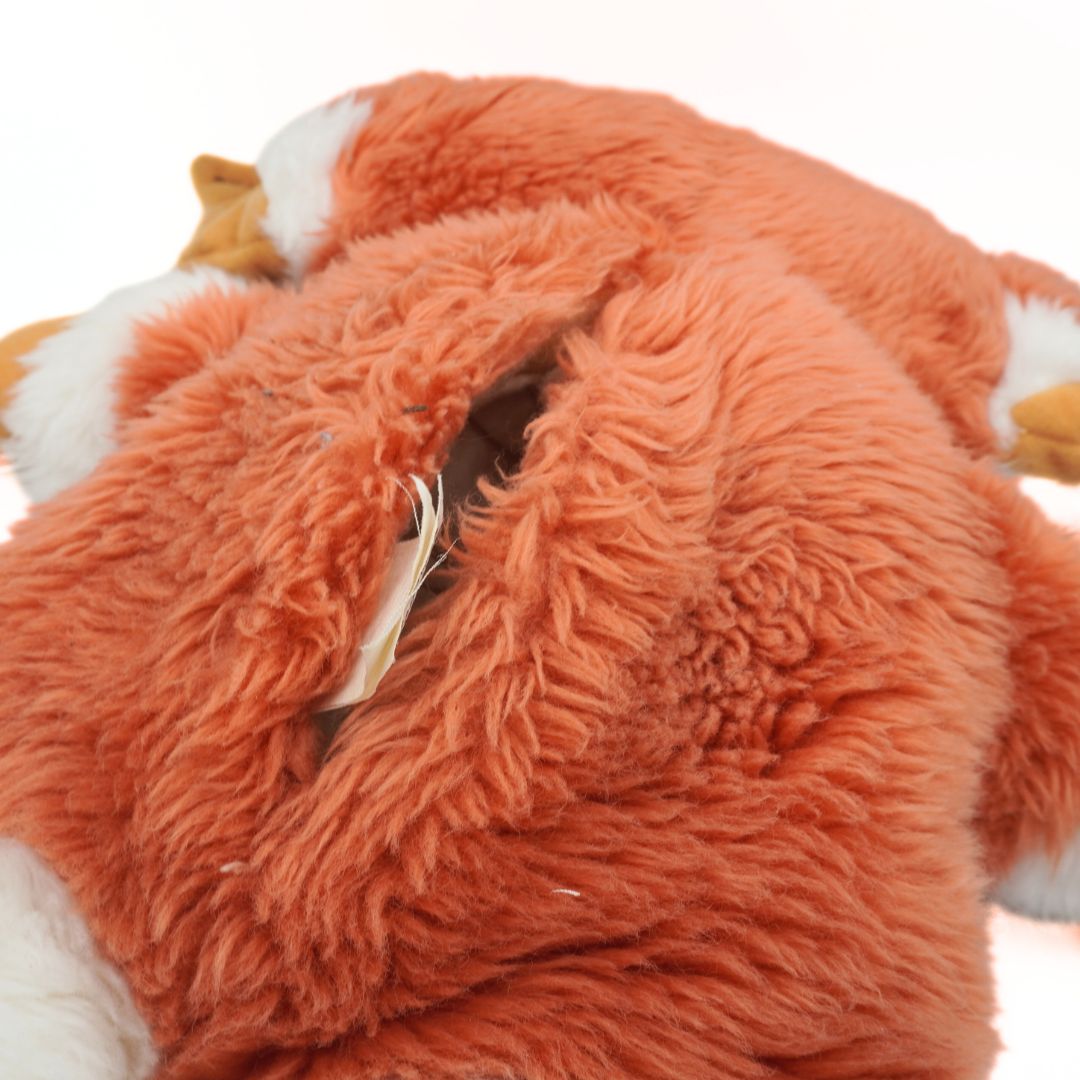Close-up of a fluffy orange and white animal toy with a white background
