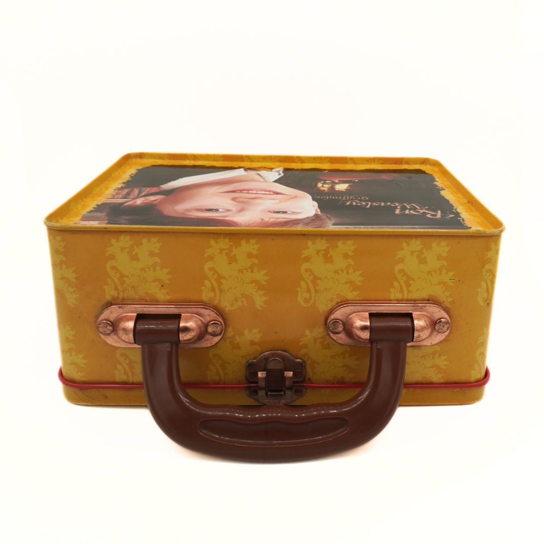 Small yellow lunchbox with decorative pattern and brown handle on a white background