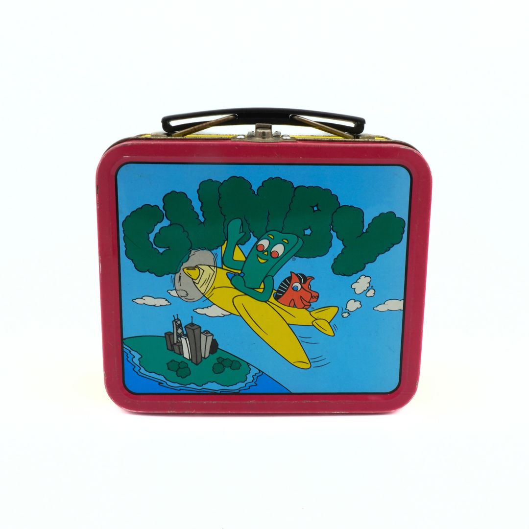 A vintage 1999 Gumby lunchbox with Gumby and Pokey riding a yellow airplane