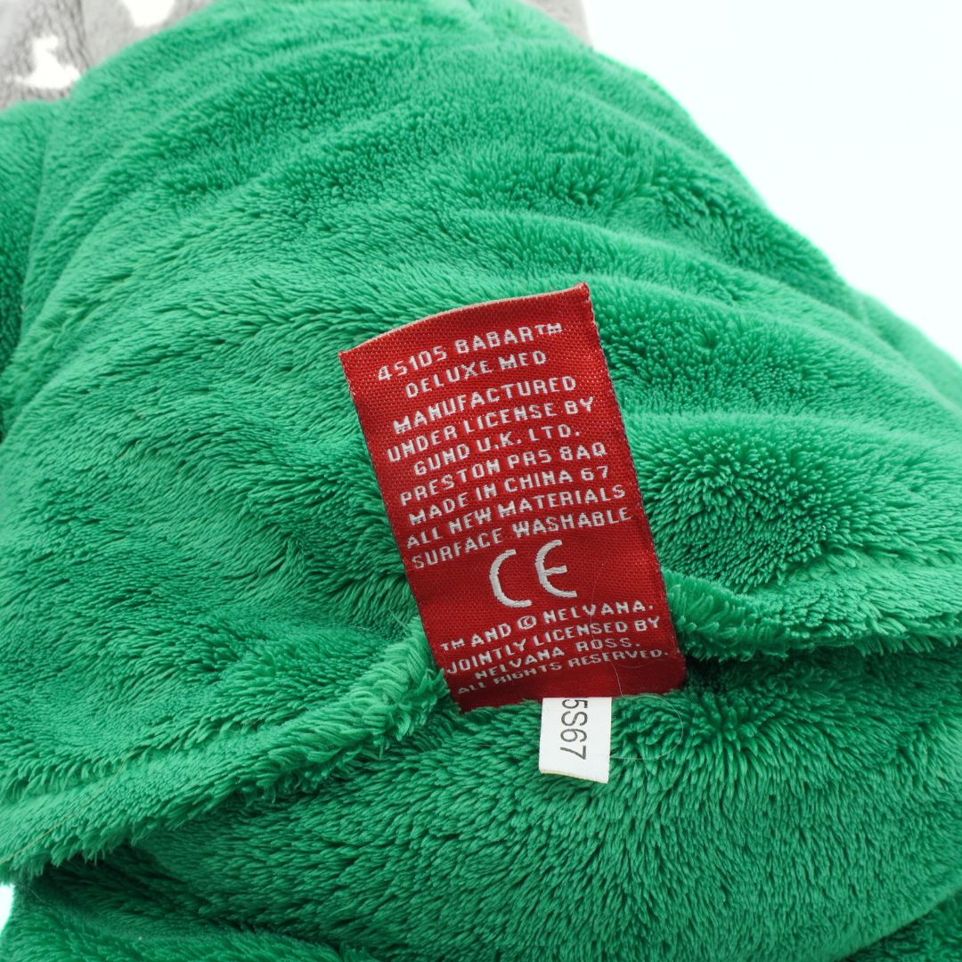 Green plush toy with a red label on a white background