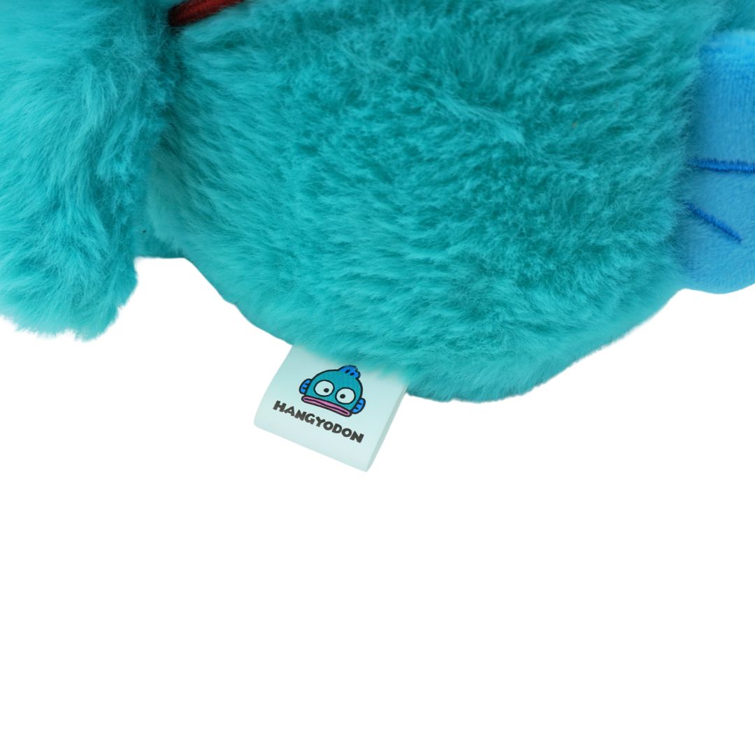 A white tag on a blue-green Hangyodon plush