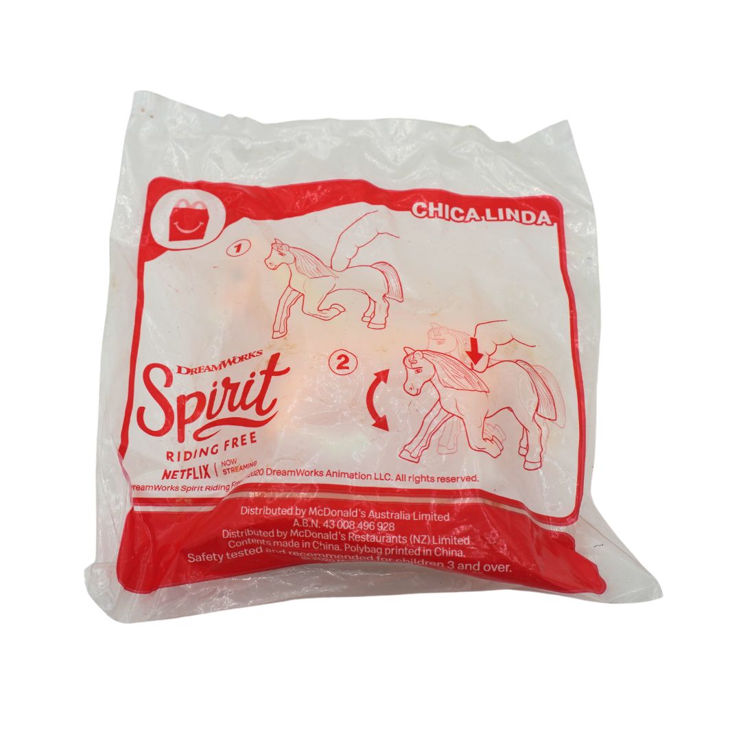 A sealed plastic bag containing a McDonald's Happy Meal toy featuring Chica Linda riding the Spirit droid from the Netflix series DreamWorks. The packaging has a white background with red printed graphics and text.