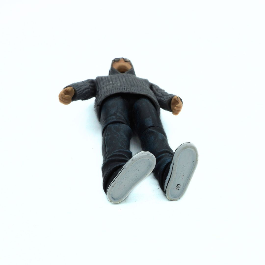Toy figure of a person wearing a sweater and pants on a white background