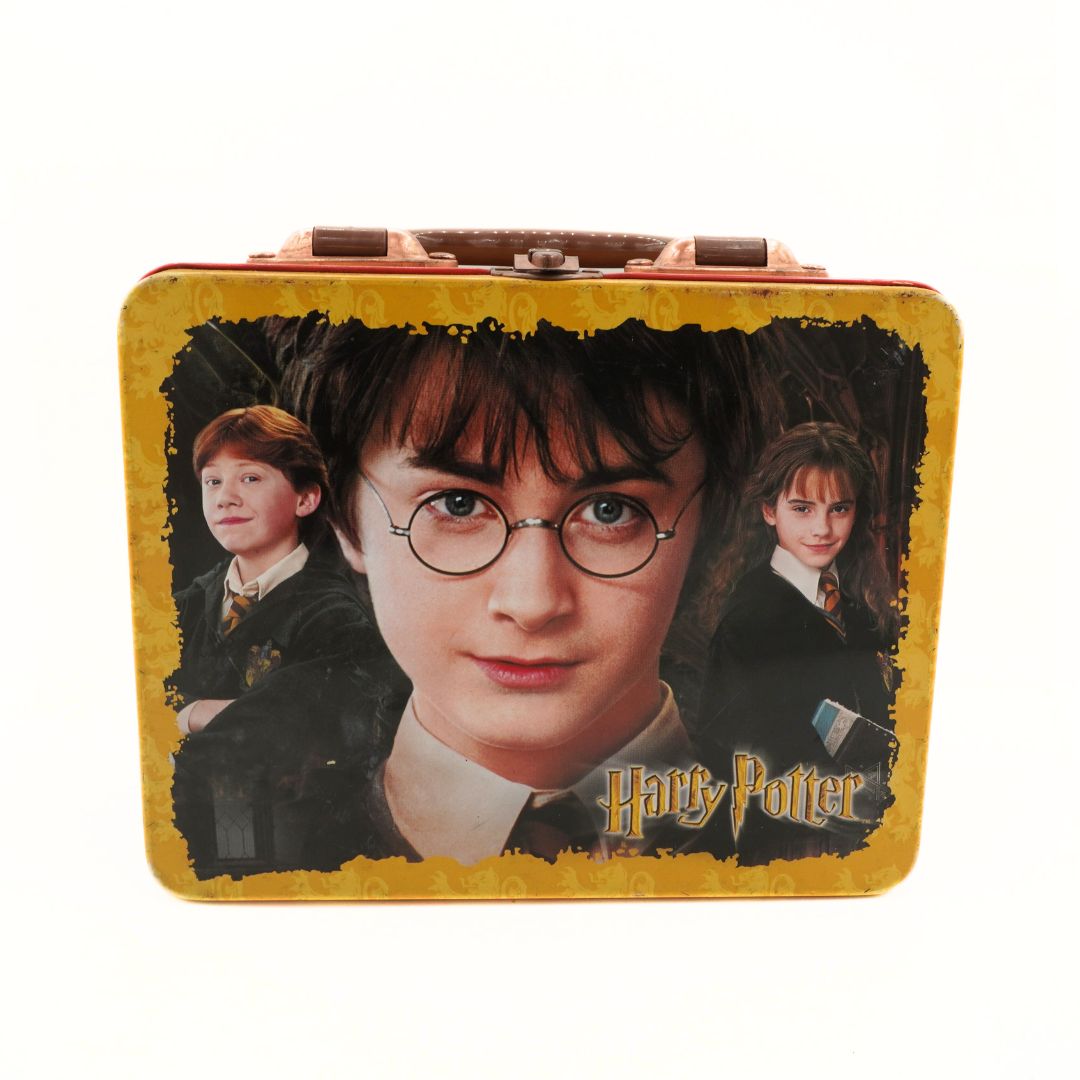 Harry Potter lunchbox with images of Harry, Ron, and Hermione on a yellow background