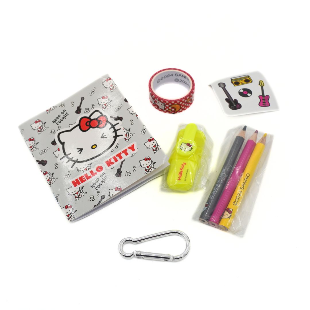 A Hello Kitty themed stationery and accessory set on a white background, including a Hello Kitty notebook, washi tape, sticker, highlighter, colored pencils, and a carabiner.