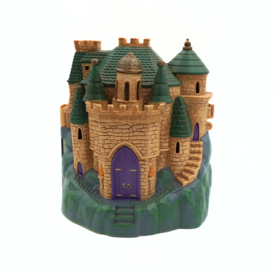 Toy castle with green roof and purple door on a white background