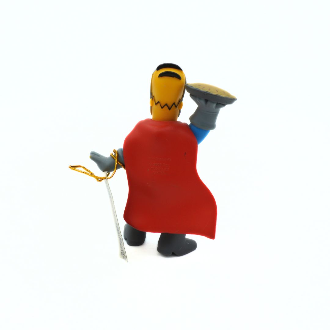 Toy figure of a character with a red cape and yellow face on a white background