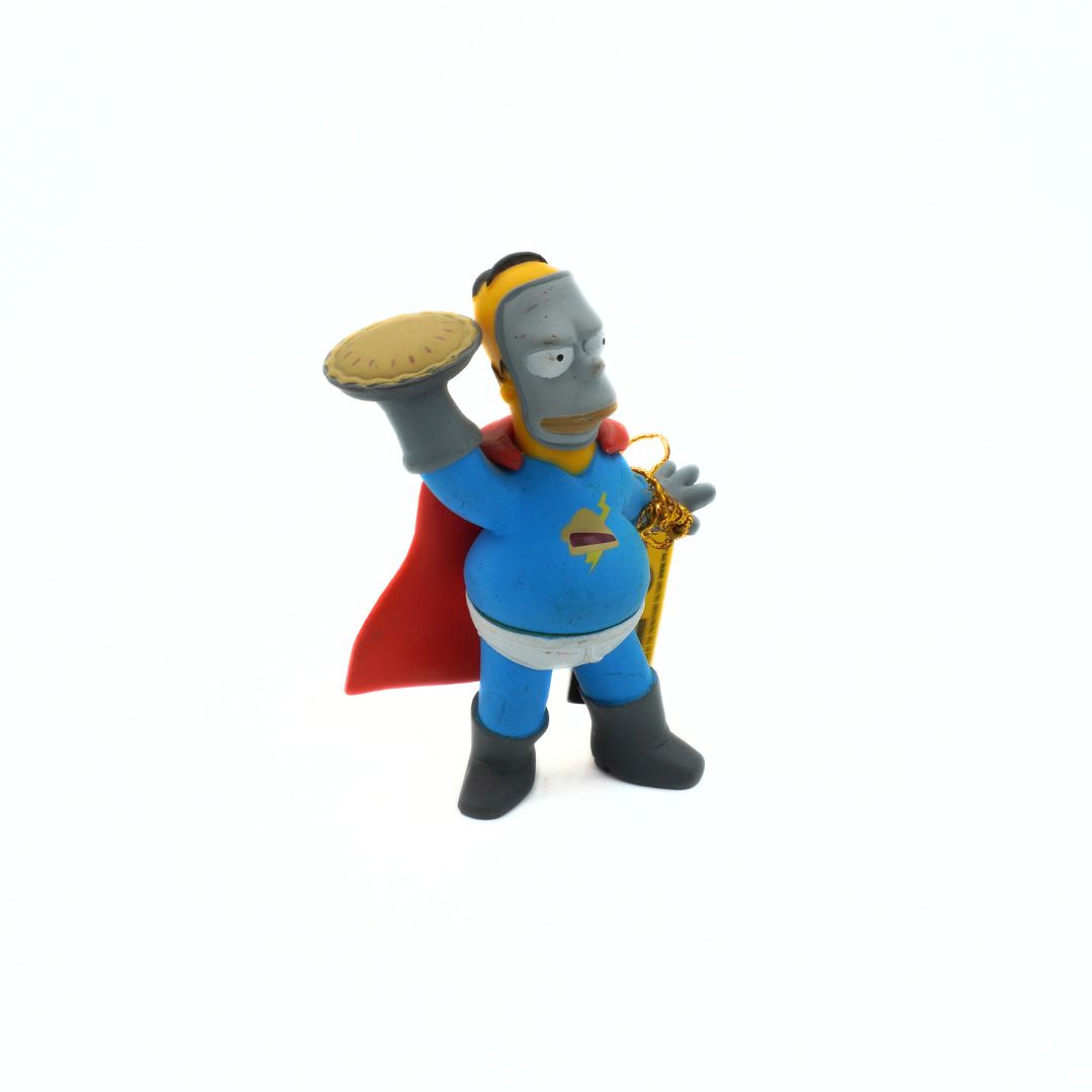 Toy figure of a character from 'The Simpsons' with a red cape and yellow hat on a white background