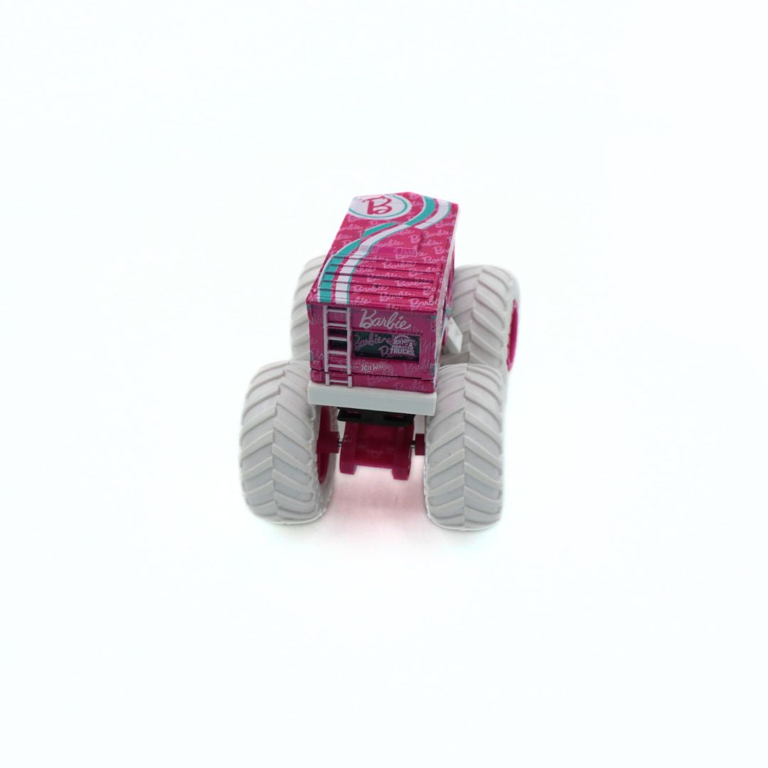 A pink toy monster truck with large gray wheels and a ladder, featuring the Barbie logo on the cab, set against a plain white background.
