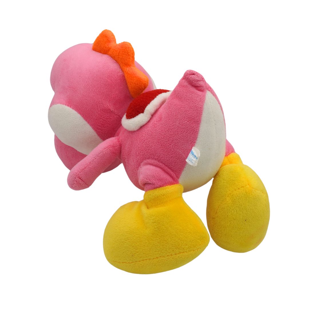 Plush toy with pink body, yellow legs, and orange bow on a white background