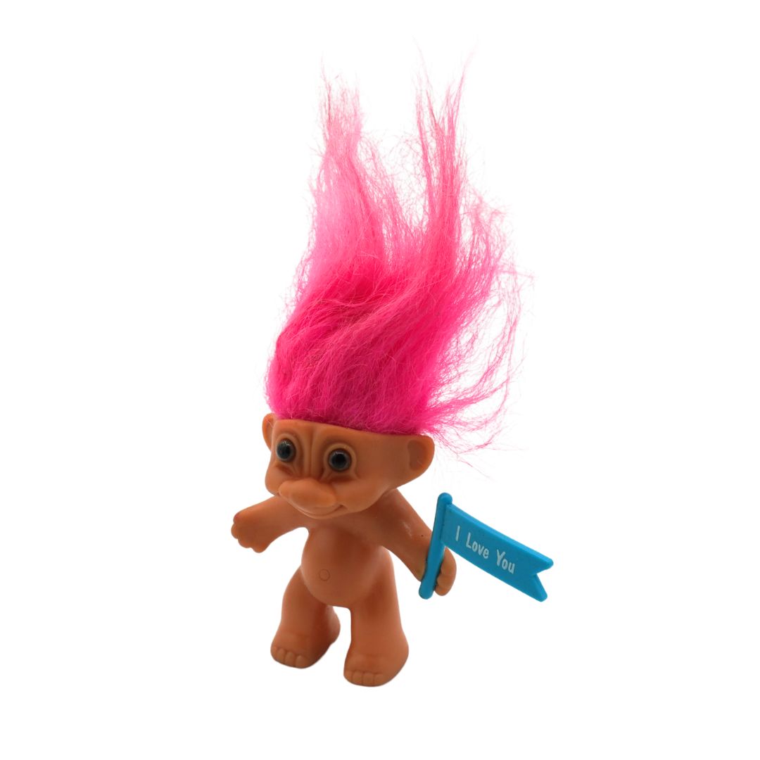 Toy figure with pink hair holding a 'I Love You' sign on a white background