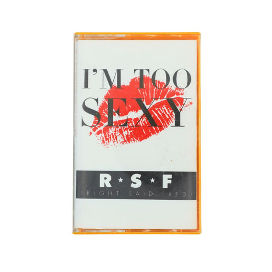 A cassette tape with a clear plastic case and orange border, featuring the text 'I'M TOO SEXY' in black over a red lipstick mark, and 'R*S*F [RIGHT SAID FRED]' on a black bar at the bottom.