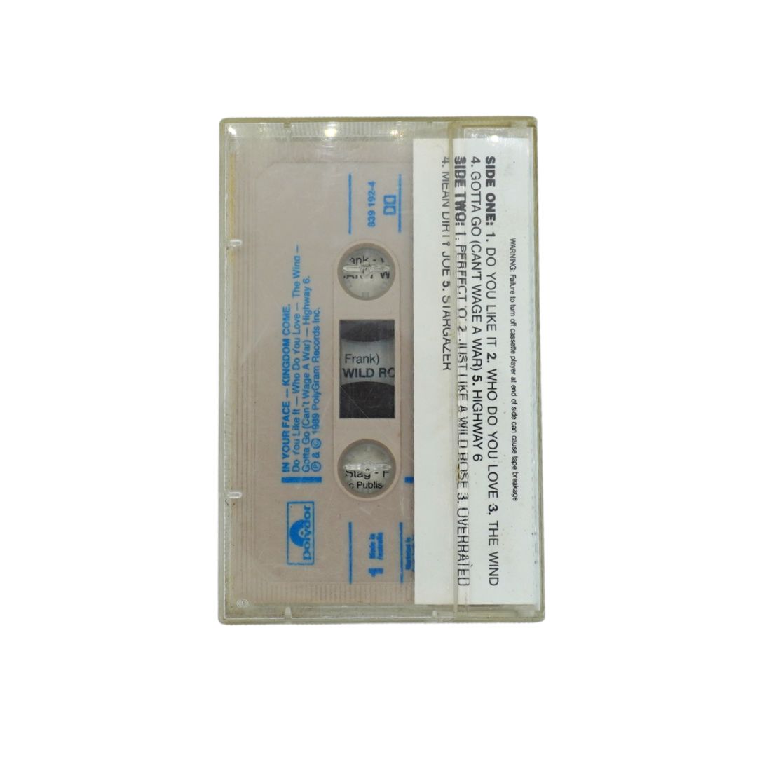 A vintage cassette tape of Kingdom Come's In Your Face, shown in a clear plastic case against a white background.