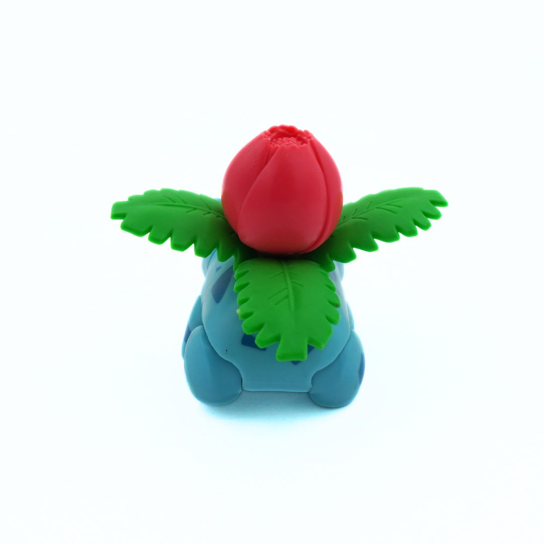 Toy figure of a blue creature with a red flower on its head against a white background