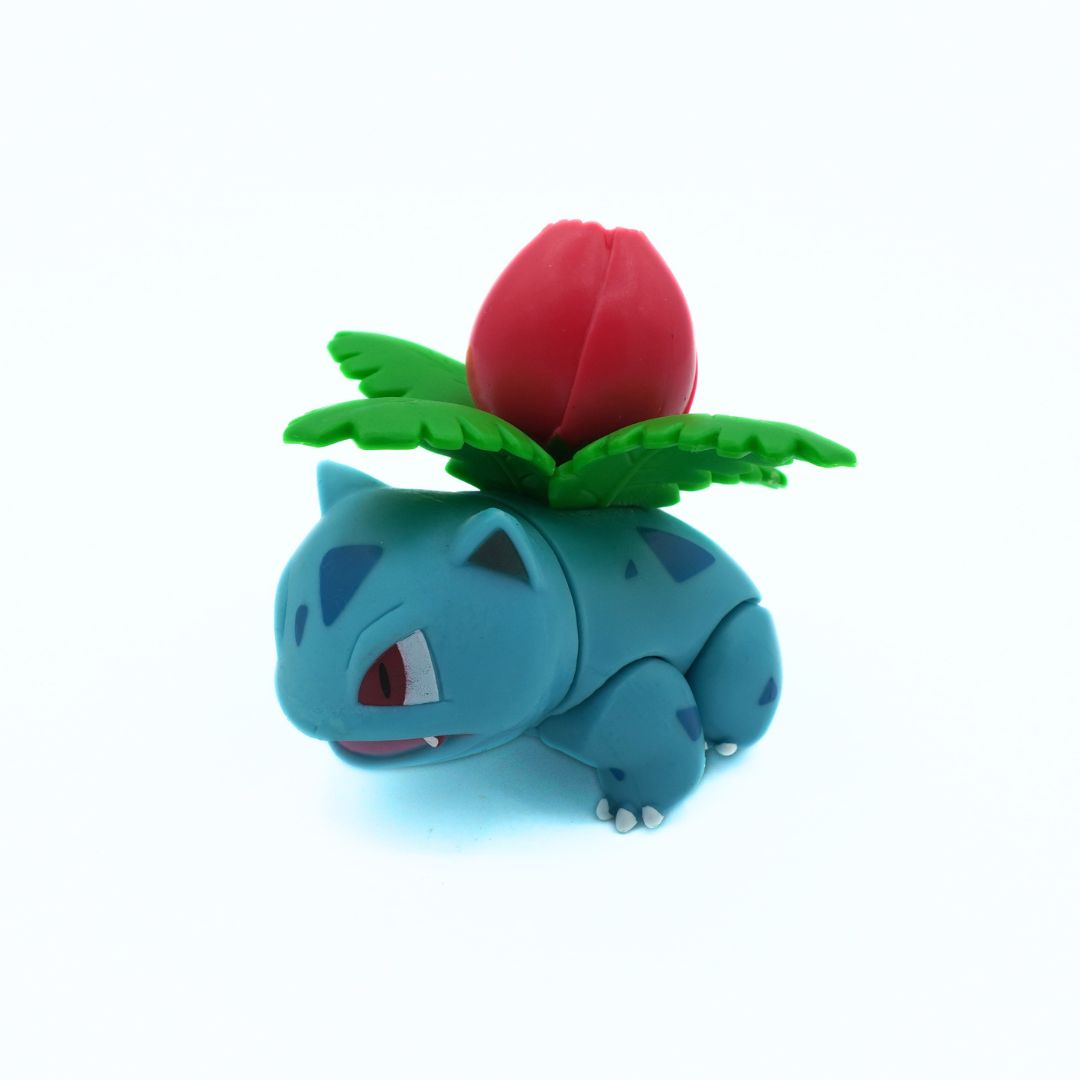 Toy figure of a blue creature with a red flower on its head against a white background