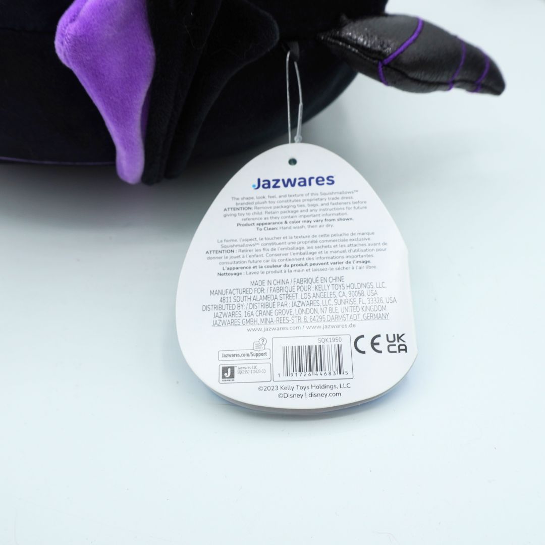 A close-up of a Jazwares plush toy showing its black fabric body, purple ear, and attached white product tag with text and barcode on a light background.