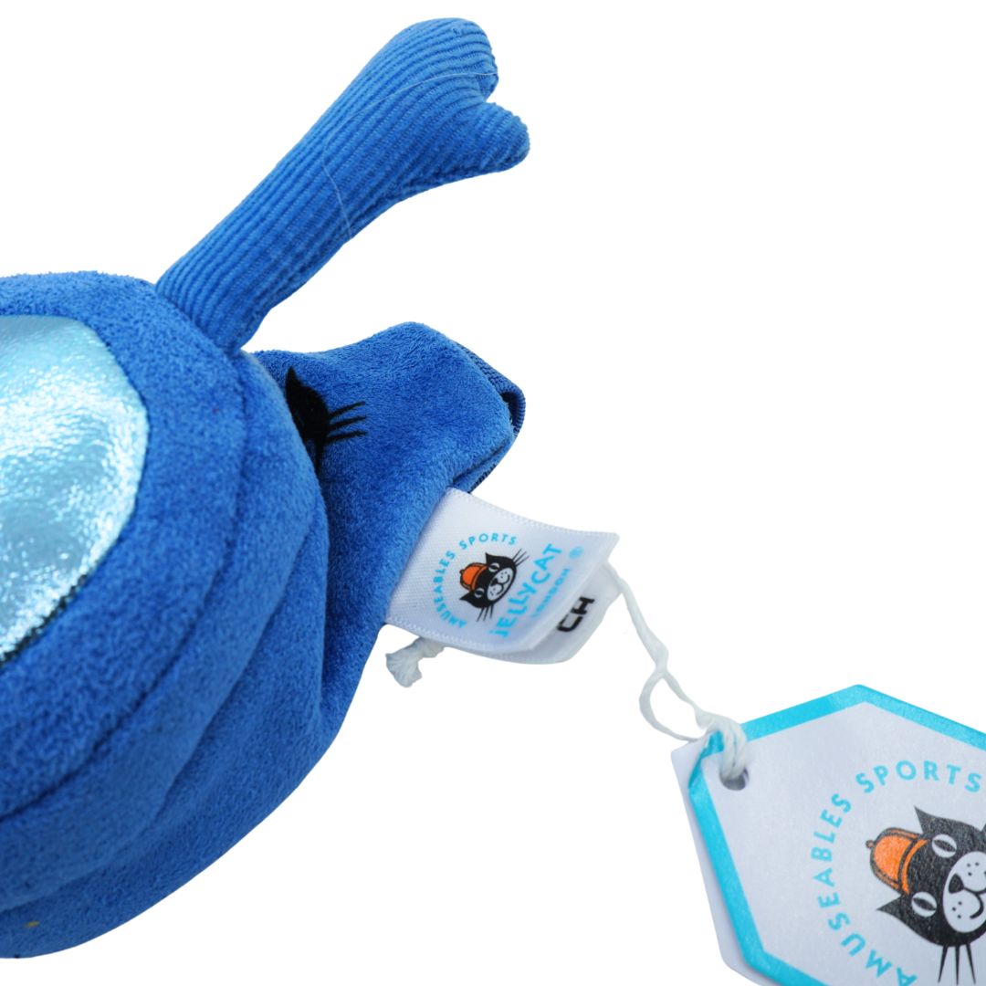 A close-up of a blue plush toy with a ribbed corduroy-like ear, attached to a white sewn-on tag and a hexagonal retail tag for Musables Sports Recley.