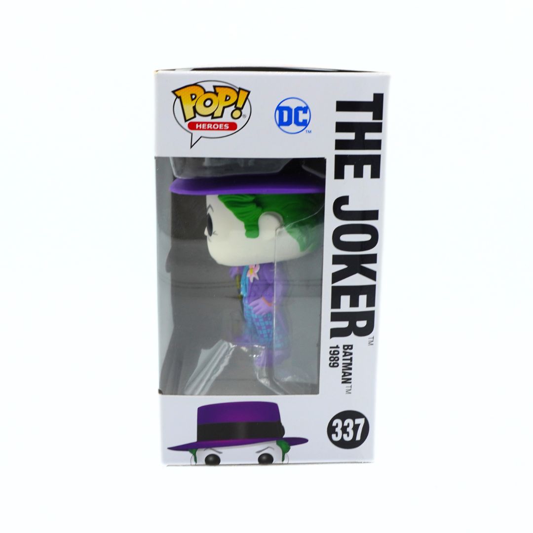 Funko Pop! Heroes The Joker vinyl figure in its original white window box packaging, featuring the character with green hair, purple suit, and black fedora hat.