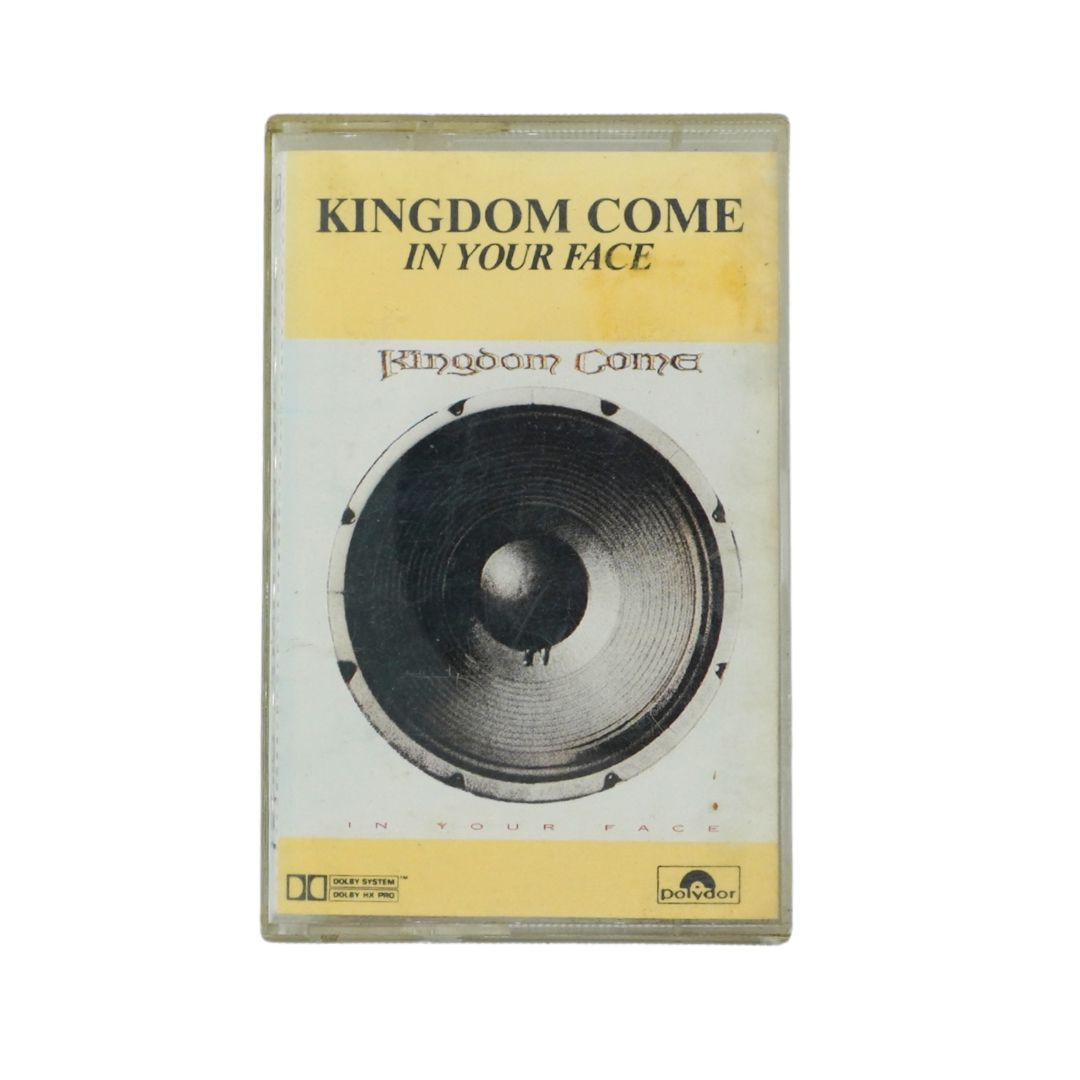 Kingdom Come In Your Face cassette album cover by Kingdom Come, featuring a large black speaker graphic on a light background with pale yellow bands at the top and bottom.