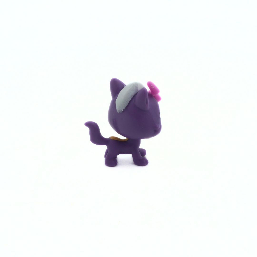 Small purple figurine with a white headband and pink bow on a white background