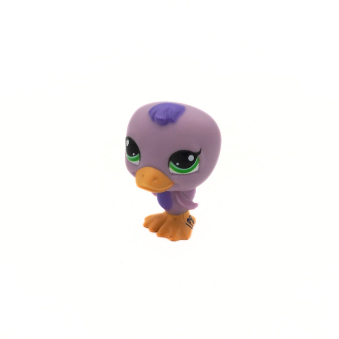 Small purple toy figure with green eyes and orange beak on a white background