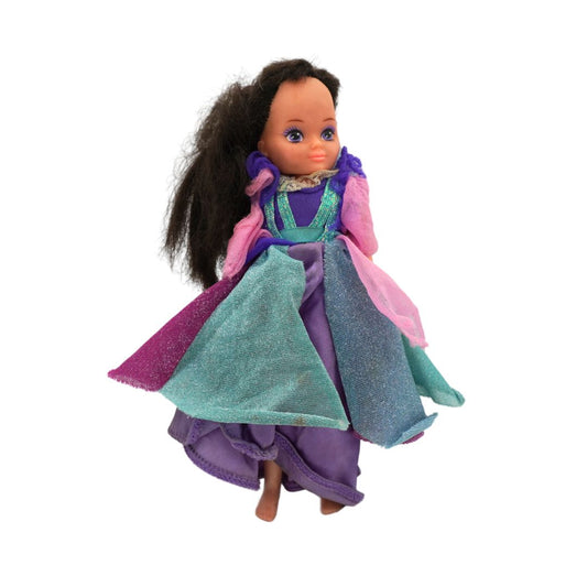 A vintage collectible doll with long dark brown hair, wearing a glittery teal and purple gown with pink sleeves, set against a plain white background.