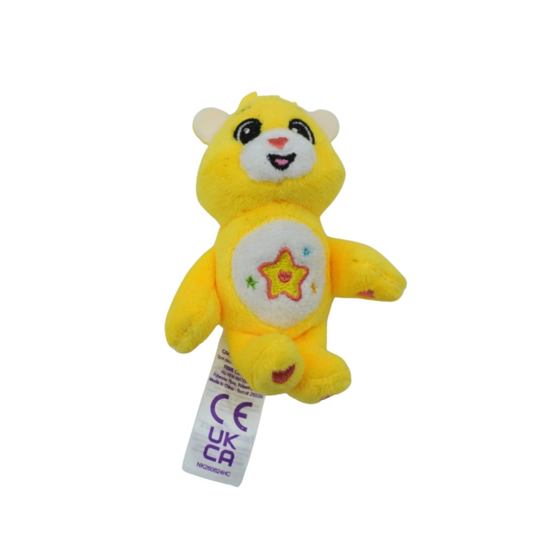 A small yellow plush bear toy with a white belly patch featuring a star design, attached to a white UKCAI tag, shown against a plain white background.