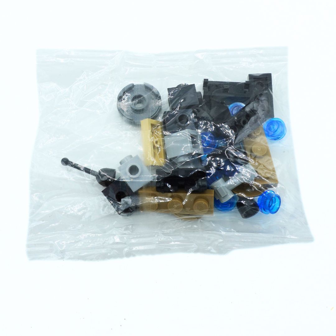 A clear plastic bag containing assorted small building block pieces, including black, gray, tan, and blue pieces, photographed on a white background.