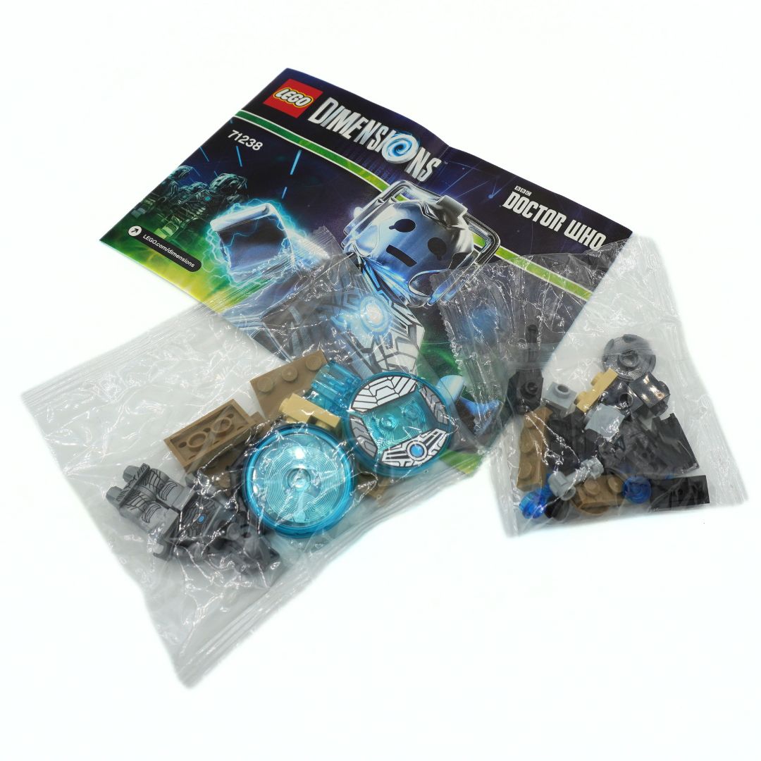 LEGO Dimensions Doctor Who set 71238, showing the original instruction booklet, a clear plastic bag with gray and blue pieces, and another bag with black and brown minifigures on a white background.